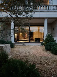 A modern residential exterior featuring stone materials and a well-lit interior through large windows.