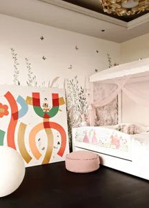A children's bedroom featuring a colorful mural on the wall and a white canopy bed with pink drapes.