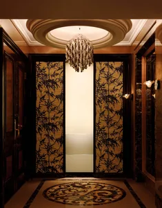 A luxurious entrance area featuring elegant elevators enclosed in glass and framed by rich, wooden elements.