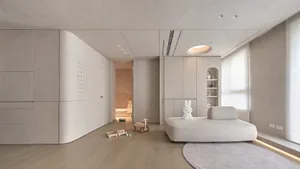 A minimalist bedroom with a fabric seating area, white cabinetry, and modern design elements.