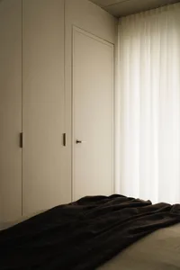 A minimalist bedroom with a fabric bedspread and wooden elements.