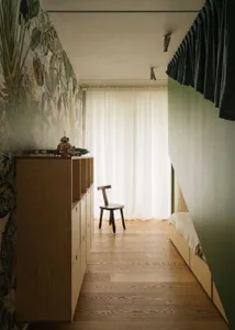 Minimalist bedroom with wooden furniture, including a wooden chair and a wooden dresser with shelves.