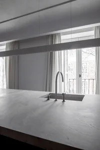 A minimalist kitchen with a concrete countertop and a modern sink.
