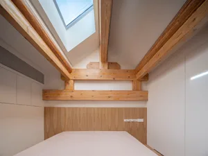 A modern bedroom with white lighting and wooden elements.