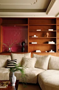 A modern living room featuring a comfortable couch adorned with plush cushions and throw pillows, alongside a bookshelf fille