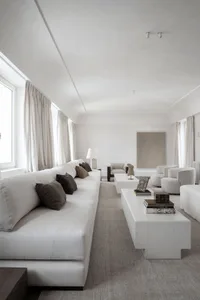 A modern living room featuring a monochromatic color scheme with fabric furniture and minimalist decor.
