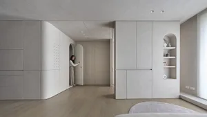 A modern minimalist apartment with concrete walls and wooden flooring.
