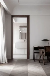 A minimalist bedroom with a terrazzo floor and light wooden furniture, featuring a bathroom with a terrazzo vanity sink and m