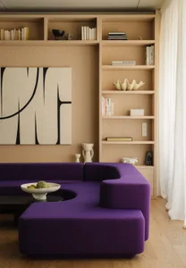 A modern living room featuring a purple sectional sofa and a built-in bookshelf filled with books and decorative items.