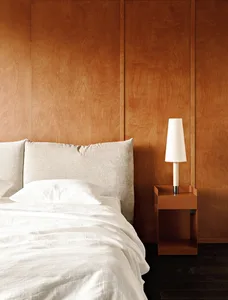 A minimalist bedroom with wooden panels and a white bed.