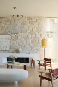 A minimalist living room with stone walls, wooden floors, and modern furniture.
