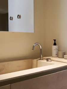Modern bathroom interior with a white terrazzo countertop and sleek chrome faucet and sink.