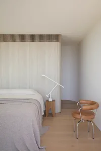 A modern bedroom featuring wooden elements, minimalistic design, and a comfortable bed.