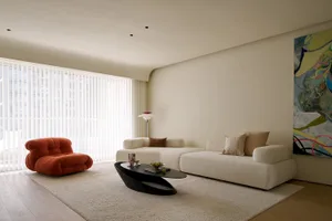 A modern living room featuring a comfortable sofa and couch, with an abstract painting, minimalist decor, and floor-to-ceilin