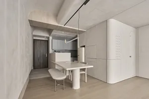 A modern kitchen with minimalist design, featuring a concrete table and bench.