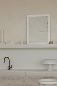 Modern kitchen with marble countertops, minimalist design style, and white floating shelves.