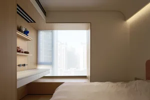 A serene, minimalist bedroom with a window overlooking a cityscape, featuring a wooden bed frame and sleek, white furnishings
