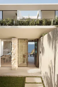 Modern residential exterior featuring stone, glass, and metal elements.