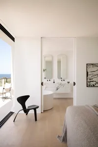 A modern residential interior featuring a marble bathroom with a round bathtub, double vanity, and floor-to-ceiling windows.