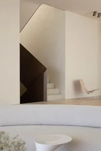 A modern living room featuring a white sofa and a sleek, white staircase.