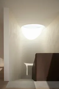 A modern stairwell with smooth concrete walls and a circular light fixture at the top.