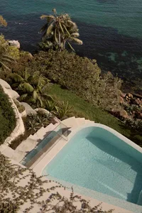 A modern pool with a terrazzo finish overlooks the ocean.