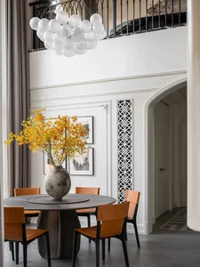 A modern dining room featuring a concrete table, leather chairs, and a glass chandelier.
