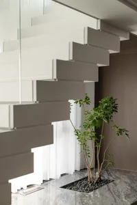 Modern staircase with floating steps and a potted plant on a marble floor.