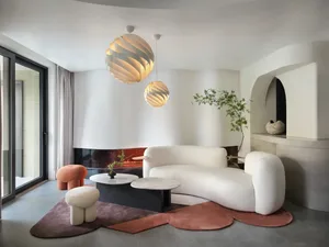 A modern living room featuring a white sofa, marble coffee table, and concrete fireplace.