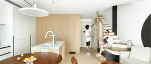 A modern living room with wooden minimalist design, including a white sofa, a white dining table, and a cat climbing a wooden