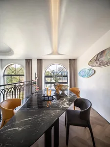Marble dining table with a vase of flowers in the center, located in a modern interior space.