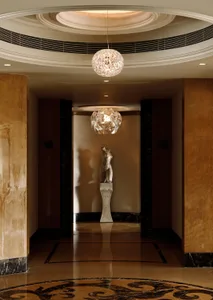 A modern marble lobby with decorative lighting and a statue.