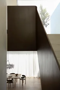 Modern minimalist dining room with wooden table, black chairs, and white curtains in front of a large window.