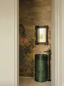 A traditional bathroom with marble walls, a green marble sink, and a framed mirror hanging above it.