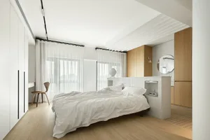 Modern minimalist bedroom featuring a platform bed with white tiled walls and wooden accents, surrounded by sheer curtains an