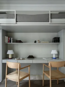A minimalist bedroom with bunk beds and a built-in desk.