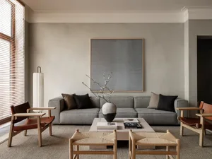 Minimalist living room featuring a concrete floor, fabric sofa, wooden chairs, and a concrete coffee table.