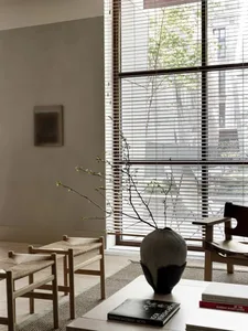 A minimalist living room featuring wooden furniture, glass windows, and metallic accents.