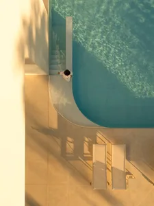 A minimalist swimming pool with concrete stairs and chairs.