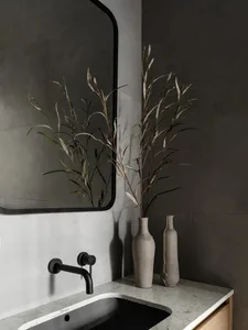 A modern bathroom interior with a black sink, gray marble countertop, and dark gray walls.