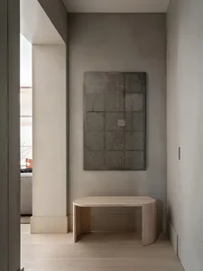 A minimalist entryway featuring a wood and concrete side table and abstract artwork.