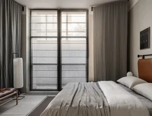 Modern bedroom with grey textiles, minimalist design, and large windows.