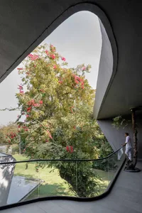 A modern house exterior with concrete walls and a tree with pink flowers in the background.