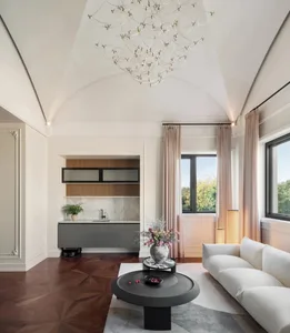 A modern living room featuring contemporary furniture, a marble coffee table, and a large window with curtains.