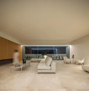 A modern living room with minimalist furniture, marble flooring, and a glass wall.
