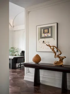 A minimalist interior with a wooden bench, abstract artwork, and natural wood elements.