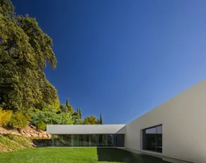A modern minimalist house featuring a concrete exterior and glass walls.