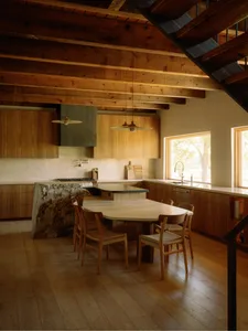 A modern minimalist kitchen with wooden furniture and appliances.