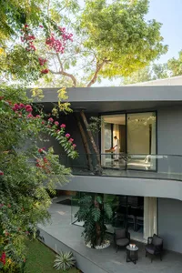 Modern residential terrace featuring concrete and glass materials, with a person preparing food in the background.