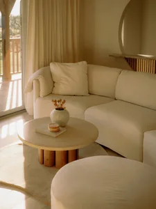 A modern, white fabric sofa in a contemporary living room setting with a round table and natural light.